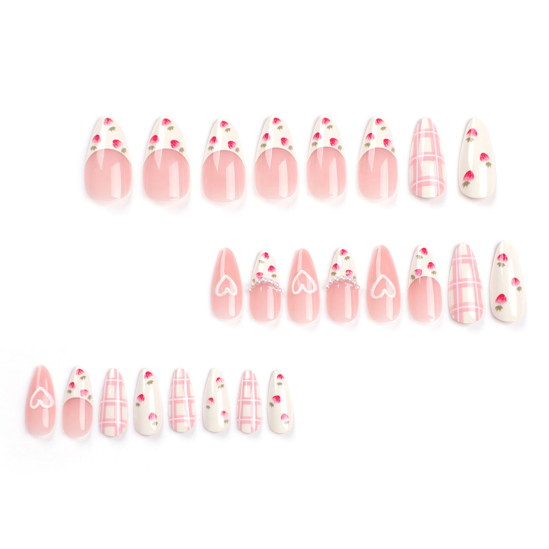 Almond-shaped press-on nails with a soft pink and white theme. The set includes French tips with tiny strawberry art, pink and white plaid patterns, and solid pink nails featuring a white hand-drawn heart outline and small pearl accents.