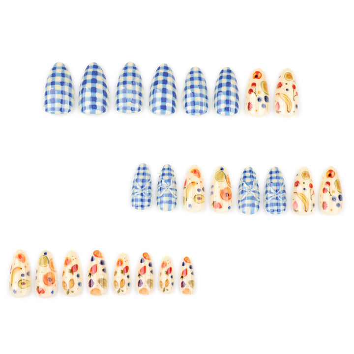 Almond shaped press-on nails with two designs: a blue and white checkered pattern and a creamy white base covered in small fruit drawings like strawberries, bananas, and blueberries.
