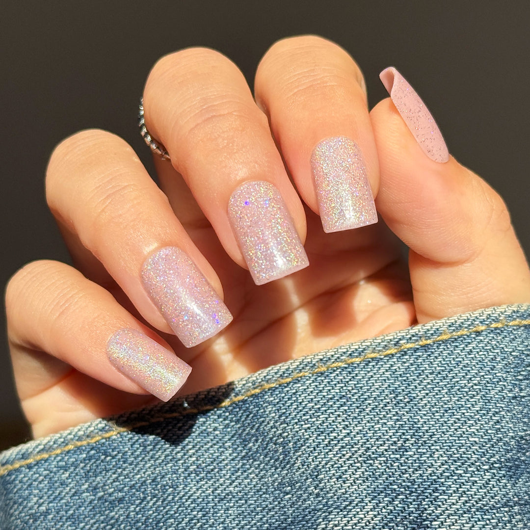 Gigi Glitz short square press-on nails featuring a soft pastel pink base detailed with a highly reflective silver-purple velvet cat-eye magnetic flash shimmer.