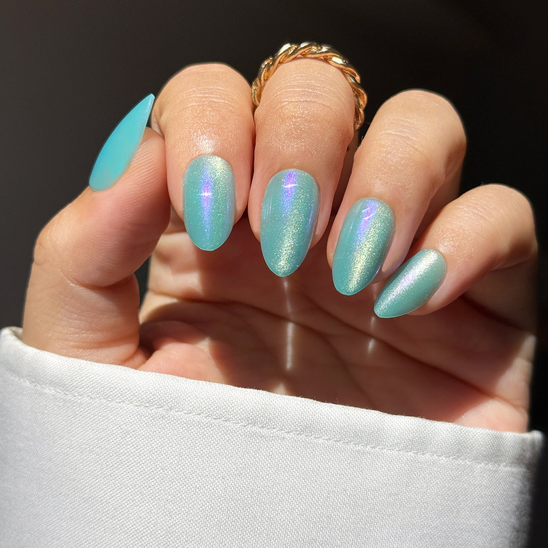 Malibu almond press-on nails featuring a vibrant aqua blue base detailed with a highly reflective silver-blue velvet cat-eye magnetic shimmer flash.