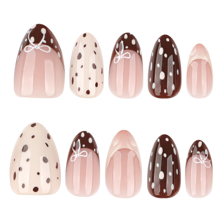 Almond-shaped press-on nails in brown and cream with polka dots, French tips, and small white bow designs.