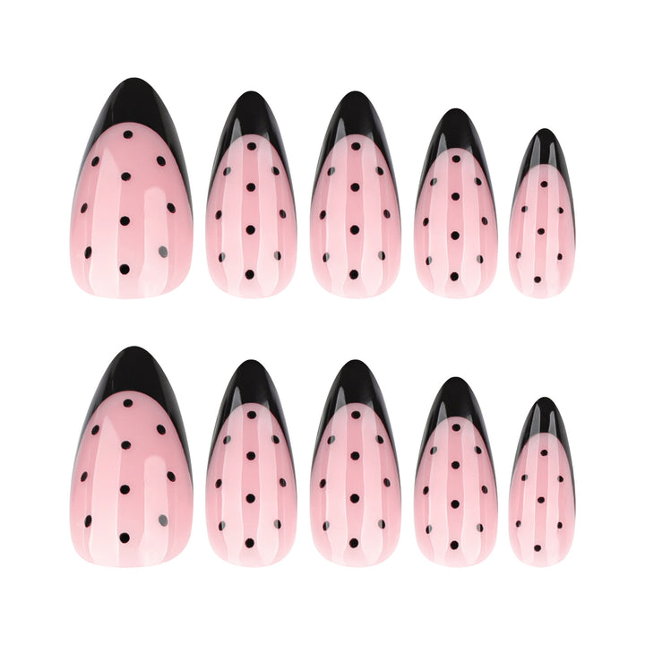 Almond-shaped press-on nails with a soft pink base, black French tips, and black polka dot nail art.