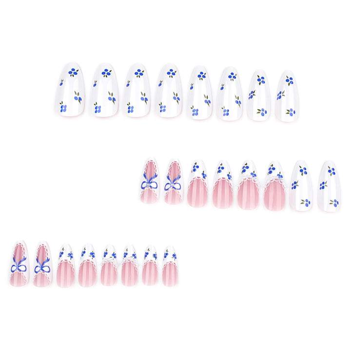 Almond-shaped press-on nails with a vintage blueberry theme. The design features all-over blueberry prints on a white base, scalloped lace French tips, and accent nails with blue ribbon bows and tiny pearl embellishments.