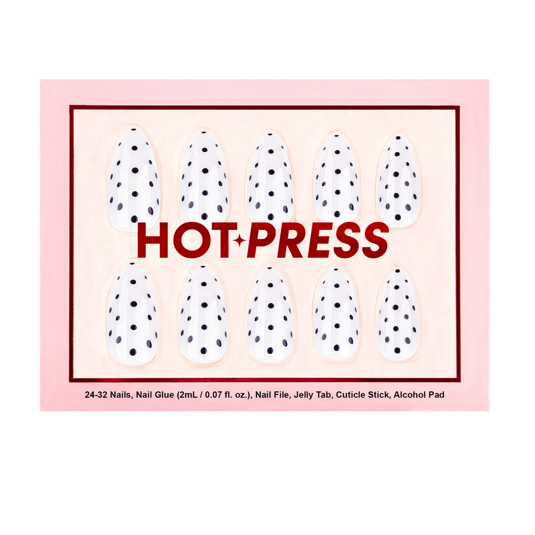 Short almond-shaped press-on nails featuring a glossy white base color and a structured black polka dot pattern resembling poppy seeds.