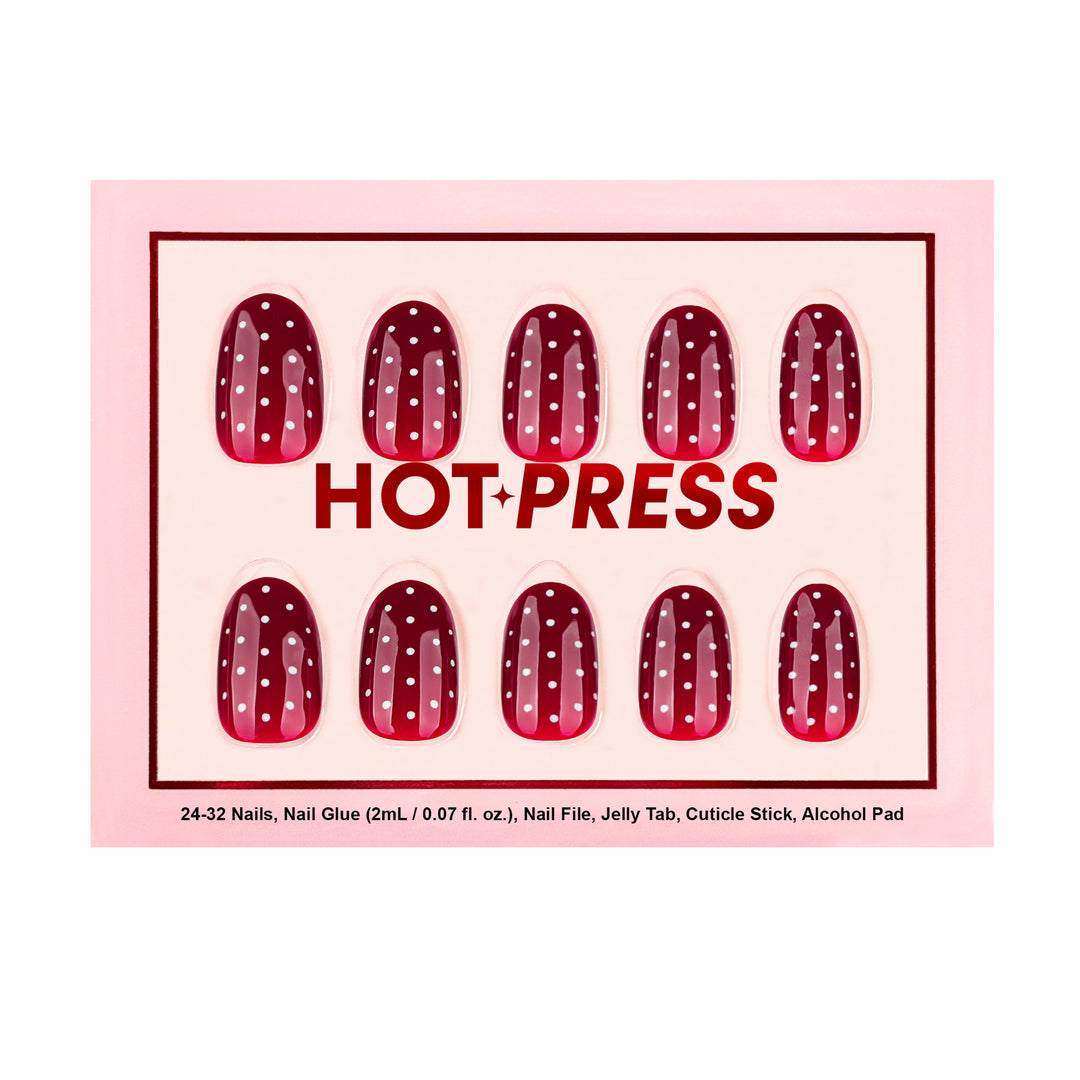 Oval press-on nails with a deep red base and white polka dots.