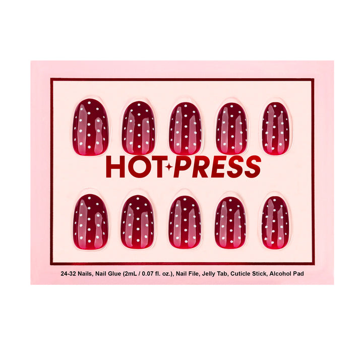 Oval press-on nails with a deep red base and white polka dots.