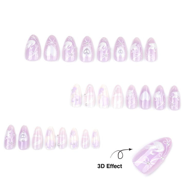 A product display showcasing multiple press-on nails from the "Sweet Devotion" collection against a clean white background. The medium-length almond nails feature a dreamy, translucent pastel lavender-purple base adorned with a fairycore bridal aesthetic, including delicate white hand-painted bows, lace hearts, textured iridescent vertical stripes, and tiny silver pearl embellishments highlighting a textured 3D effect.
