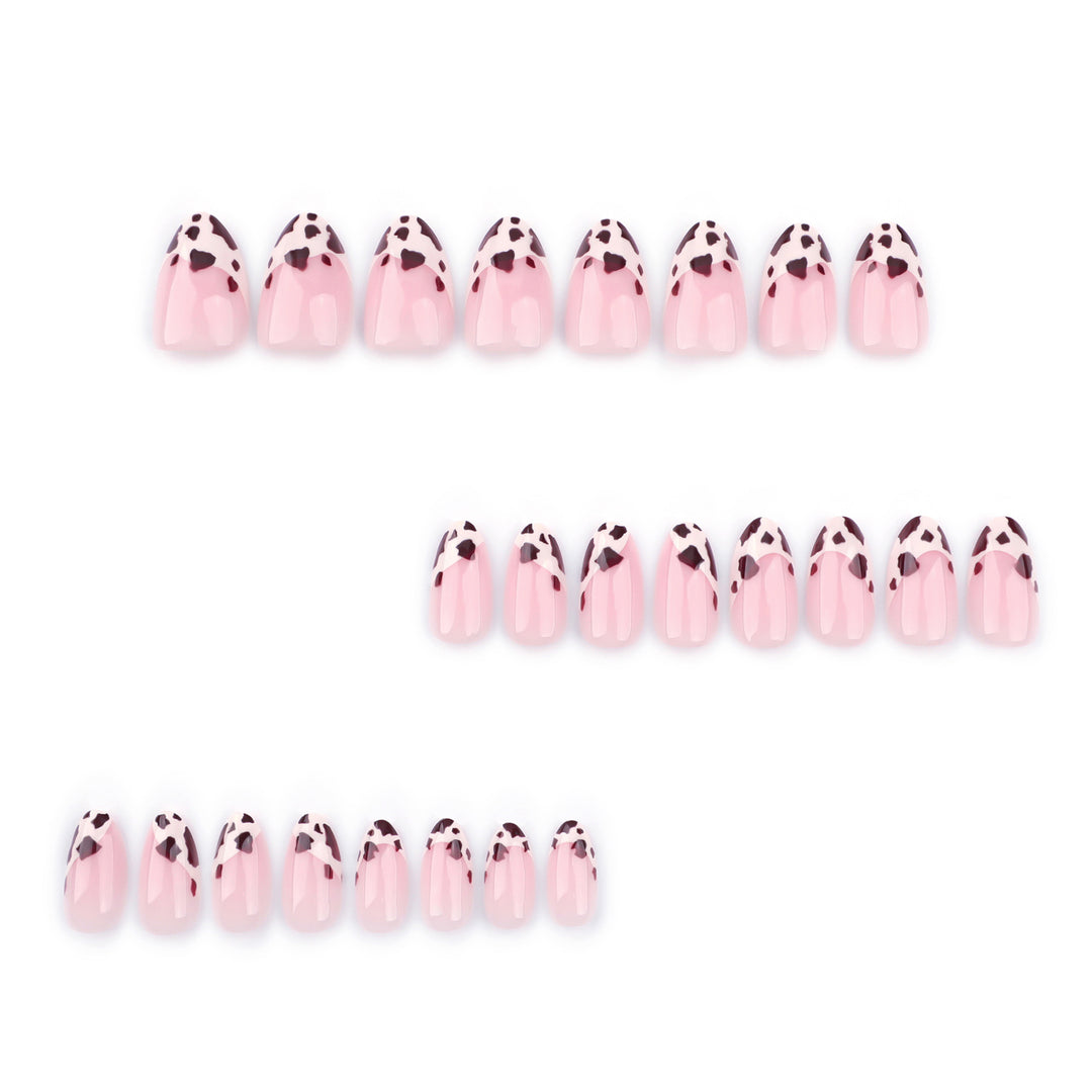 Medium almond-shaped press-on nails featuring a sheer nude base and French tips decorated with a dark brown and espresso cow print pattern. The nails have a smooth, glossy finish and are shown both in a layout and worn on a hand.
