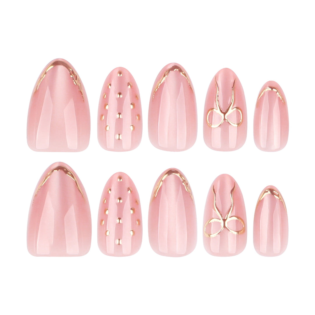 Darling Details almond bridal press-on nails featuring a sheer milky base decorated with thin gold tips, polka dots, and a coquette bow.